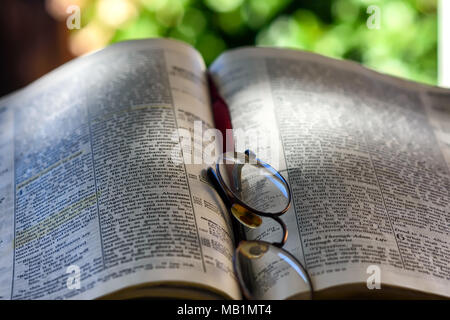 Vecchi occhiali bifocali giacciono sulla pagina biblica all aperto con camera per copiare il testo Foto Stock