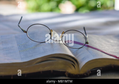 Vecchi occhiali bifocali giacciono sulla pagina biblica all aperto con camera per copiare il testo Foto Stock