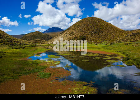 Acqua cristallina con sorgente-rossastra alghe colorate, riflettendo il cielo blu e nuvole e colline nelle vicinanze Foto Stock