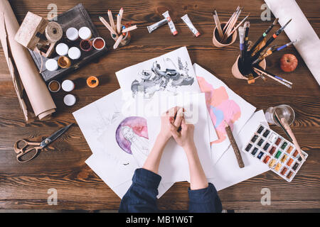 Vista in pianta parziale di mani femminili e schizzi con vernici a artista workplace Foto Stock