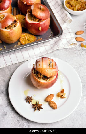 Mele cotte con muesli, cannella, noci e miele sul tavolo di pietra. Un sano dessert di frutta. Vista superiore Foto Stock