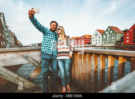 Matura in amore tenendo selfie tramite smartphone che viaggiano nella città di Trondheim in Norvegia vacanze weekend Outdoor Lifestyle case scandinavo landmarks archit Foto Stock