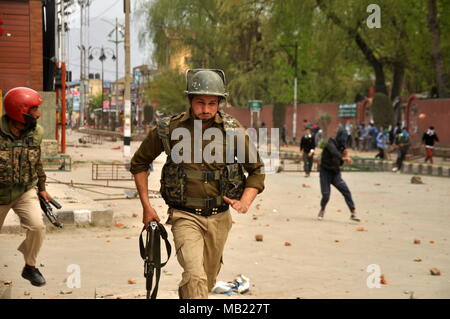 Esecuzione di polizia per coperchio dopo la pietra pesante della concia è scoppiata tra studenti e forze di governo al di fuori di Amar Singh college srinagar su Aprile 05,2018 Foto Stock