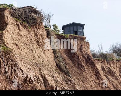 Sidmouth, 6th Apr 18. Un residente del Devon ha divertente mettere un avviso "for sale" sul suo capannone – come ora è arroccato pollici da una caduta di 100 piedi. Quattro cascate scogliera nella scorsa settimana hanno lasciato proprietà in Cliff Road, Sidmouth manca metri di giardino. La continua erosione di Pennington Point, ad est della città di Regency, ora mette in pericolo la foce del fiume Sid stesso, che se colpito potrebbe inondare una grande area della città. I costi di riparazione sono stimati a £72 milionse l'alluvione si è verificata. Foto Stock