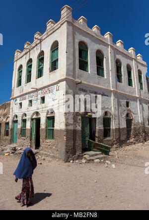 Donna somala passando davanti dell' ex impero ottomano house, provincia nordoccidentale, Berbera, il Somaliland Foto Stock