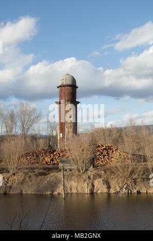 Pile di polpa di grado linea di registri il Mill road, sul cantiere, a Fodge prodotti di pasta di legno, con il vecchio Bonners Ferry legname Azienda rifiuti torre del forno in th Foto Stock