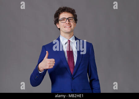 Curly-headed boy sorridente e mostrando grande pollice in alto Foto Stock