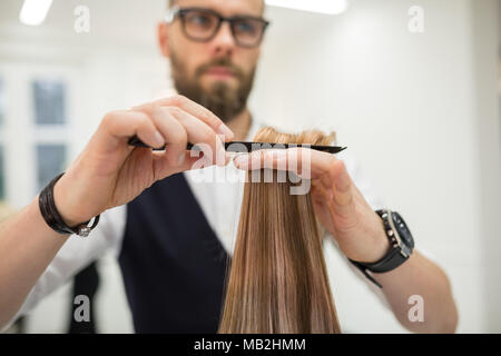 Ritagliato ritratto di parrucchiere pettinatura dei capelli del client Foto Stock