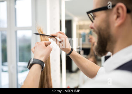 Ritratto di felice parrucchiere pettinatura dei capelli del cliente strand Foto Stock