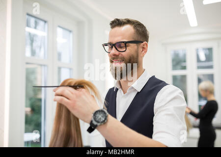Ritratto di felice parrucchiere pettinatura dei capelli del cliente Foto Stock