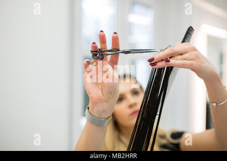 Ritratto di focalizzata parrucchiere azienda cliente ciocca di capelli per tagliare Foto Stock