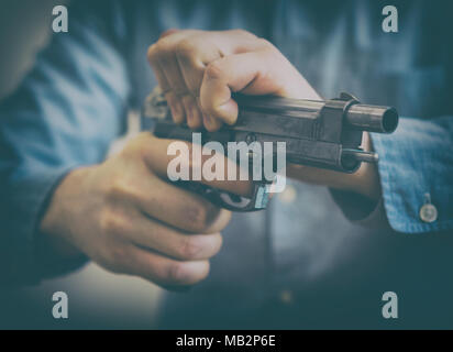 Mani maschio di ricaricare la pistola. Vista ravvicinata. Foto Stock