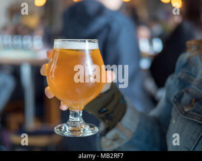 Chiudere il colpo di una donna azienda birra chiara snifter (IPA) in bar/birreria Foto Stock