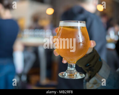 Chiudere colpo di mano azienda birra chiara snifter (IPA) in bar/birreria Foto Stock