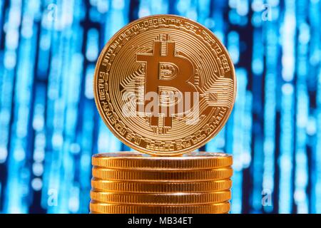 Uno bitcoin sul bordo posto sulla pila di golden bitcoins sfocata circuito blu su sfondo. Digital denaro virtuale valuta elettronica blockchain stock exchange futuro finanziamento bancario innovativi Foto Stock