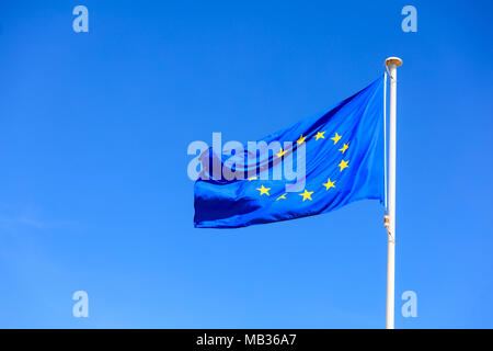 Bandiera dell'UE. Bandiera dell'Unione europea su un pennone sventolando in direzione opposta su un cielo blu sullo sfondo Foto Stock