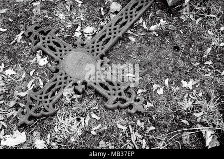 Antiquariato decorativo arrugginito croce di ferro su un cimitero di massa. Immagine monocromatica Foto Stock