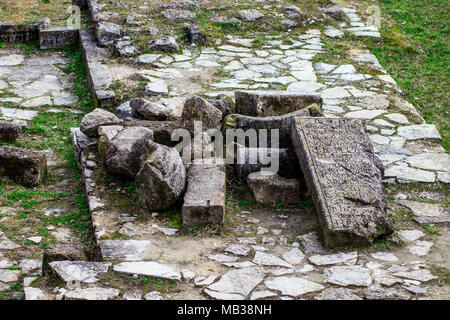 Un mazzetto di antiche di blocchi di pietra sdraiati sull'erba. Foto Stock