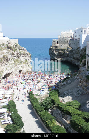Una spiaggia affollata di turisti nel comune di Polignano a mare sulla costa Adriatica, Puglia, Italia Foto Stock
