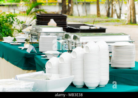 Bianco impilati pulire le piastre e bocce su un tavolo luminoso sono posizionati per servita. Foto Stock