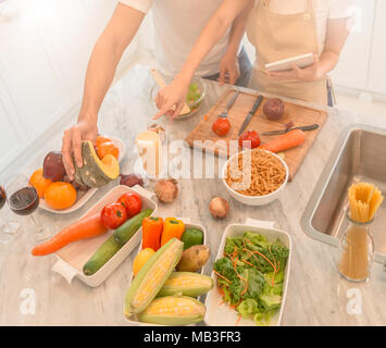 Felice coppia giovane la cucina insieme in cucina a casa. guardando il tablet pc. Foto Stock