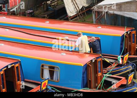 Uomini al lavoro su una chiatta / Canal Boat nel dock a Heyford Wharf, Oxfordshire, Regno Unito Foto Stock