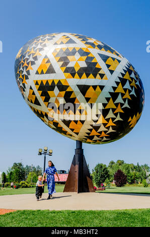 Mennonita bambini all'uovo Vegreville, una gigantesca scultura di un pysanka, un stile ucraino uovo di Pasqua. È il più grande pysanka nel mondo. Vegrev Foto Stock