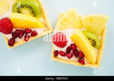 Esotiche crostate di frutta. Il burro pasticcino riempiti con creme patissiere rabboccato con ananas, kiwi, mango, lamponi e melograno Foto Stock