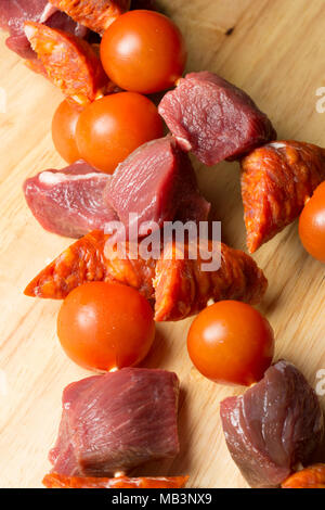 A cubetti, materie di cinghiale, il salame chorizo e pomodori ciliegia attorno alla griglia. La carne di cinghiale è molto più scura di maiale domestico e di gusti molto differiscono Foto Stock