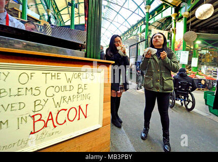 Londra, Inghilterra, Regno Unito. Due donne giapponesi strada mangiando cibo nel mercato di Borough, Southwark Foto Stock