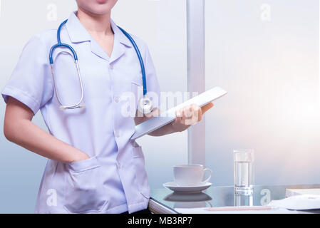 Smart donna supporto medico e paziente di contenimento grafico con stetoscopio blu collana, donna medico con uniforme in camera o scrivania Foto Stock