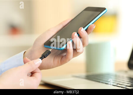 In prossimità di una donna mani collegando un caricabatterie su uno smart phone Foto Stock