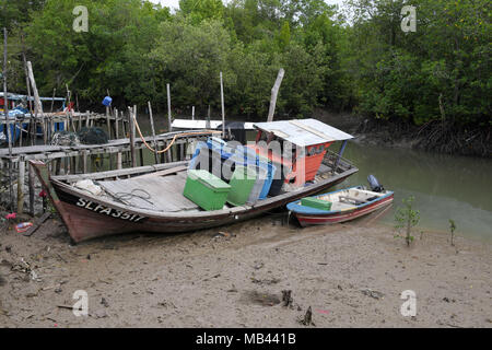 Un civile piccola barca da pesca che giace sul fango dopo il livello del mare si ritirò a Crab Island, un famoso villaggio di pescatori in Malaysia. Foto Stock