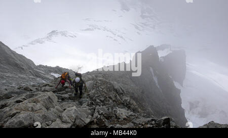 Guida di montagna e il client verso un alto vertice alpino su un nebbioso giorno Foto Stock