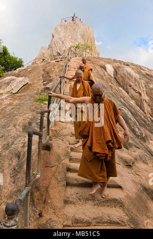 Vista verticale dei monaci buddisti scendendo dal ripido passi di Gala Aradhana rock a Mihintale montagna, Sri Lanka. Foto Stock