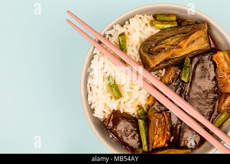 Stile cinese Melanzane Arrosto con riso bollito e fagioli verdi contro uno sfondo blu Foto Stock