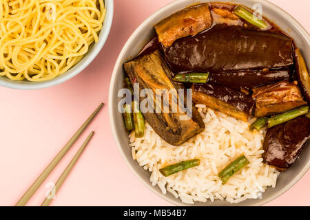 Stile cinese Melanzane Arrosto con riso bollito e fagioli verdi contro un sfondo rosa Foto Stock