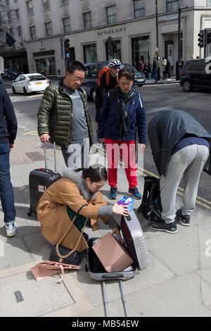 Una donna asiatica confezioni la sua valigia con gli acquisti recenti, il 6 aprile 2018, a Londra, in Inghilterra. Foto Stock