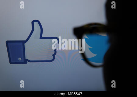 Una persona guarda Facebook e Twitter logo sullo schermo di un computer Foto Stock