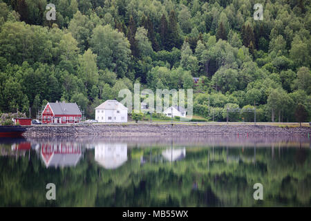 Foreste di montagna e il villaggio con la riflessione in acqua del Hardanger fiordo, Norvegia Foto Stock