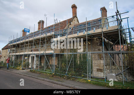 Impalcatura sulla casa pubblica Falcon Castello Ashby Northamptonshire Inghilterra ripara edificio vecchio stile segni stile fattoria edificio pietra metallica Foto Stock