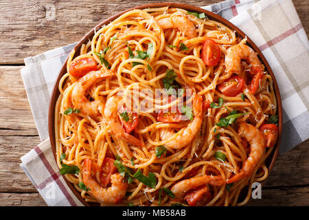 La pasta italiana spaghetti con gamberi e parmigiano ed erbe nel pomodoro salsa diavolo di close-up su una piastra superiore orizzontale vista da sopra Foto Stock