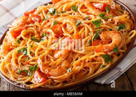 Cucina Italiana Spaghetti con gamberetti, parmigiano e le erbe in pomodoro fra diavolo sauce close-up su una piastra orizzontale. Foto Stock