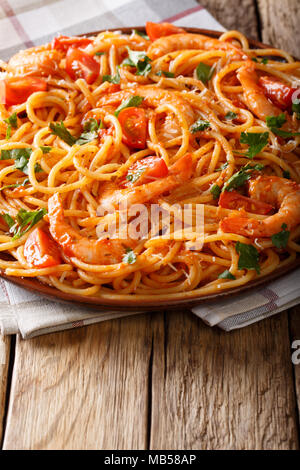 Spaghetti con gamberetti con salsa al diavolo di close-up su una piastra su un piano verticale. Foto Stock