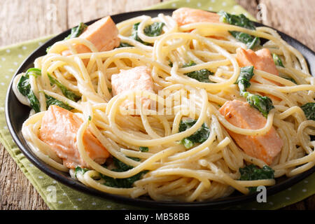 Spaghetti fatti in casa con pasta al salmone, crema di formaggio e spinaci closeup su una piastra sul tavolo orizzontale. Foto Stock
