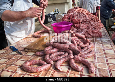 Il macellaio rende salsicce fatte in casa all'aperto in un modo tradizionale. Foto Stock