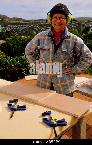 In modalità di pausa tra i tagli di falegnameria, una donna è pronta per la fascetta di fogli di legno compensato per il taglio successivo Foto Stock