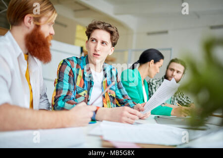 La gente di affari di sedere a tavola e lavorare con documenti e discutere le idee Foto Stock