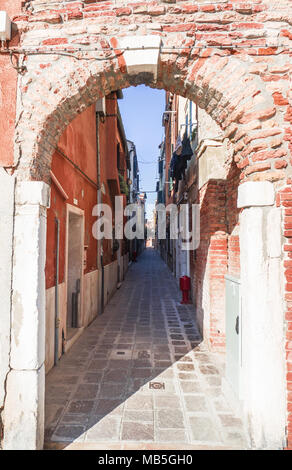 Accesso a un vicolo stretto da un mattone portale ad arco. Venezia, Italia Foto Stock