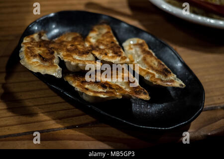 Gyoza fritte servite con cura su una piastra nera noto anche come gnocchi di giapponese Foto Stock